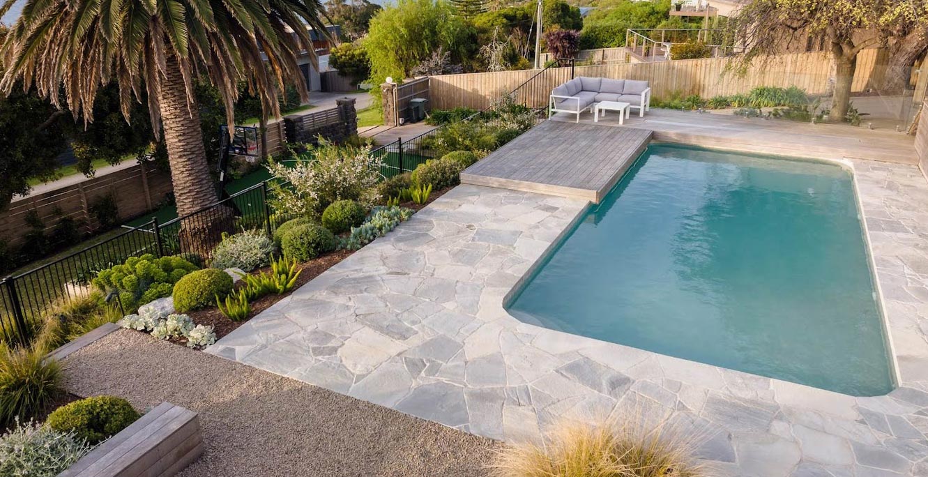 Garden swimming pool with natural stone crazy paving and timber decking